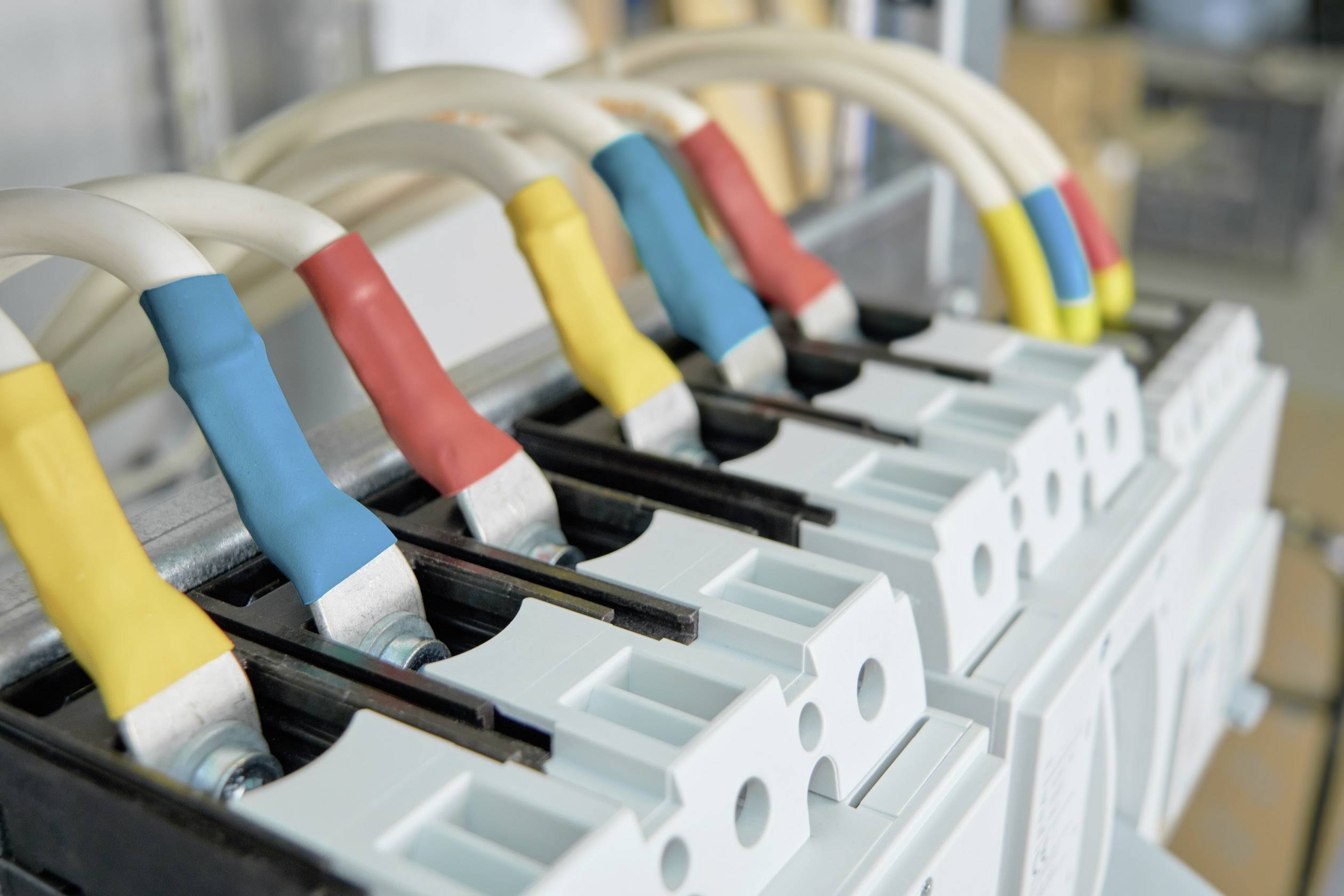 Elektrické káble v rôznych farbách sú pripojené k elektrickým svorkám. Reprezentujú rôzne fázy alebo vedenia.