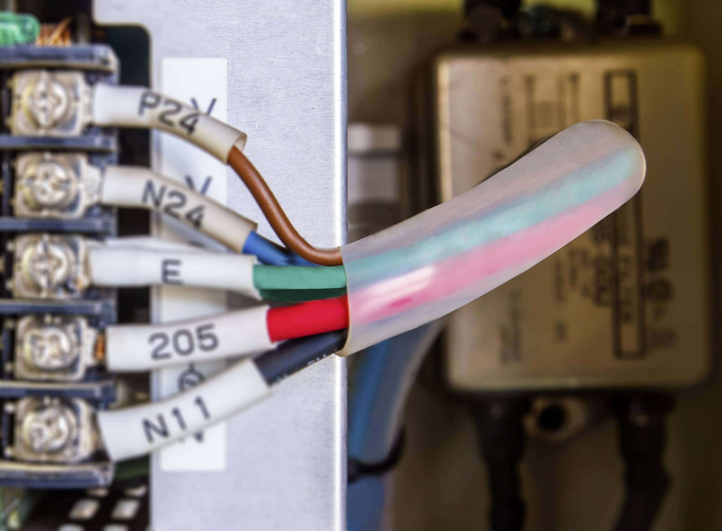 Údržbár pracuje na rozvádzači s rôznorodými káblami a pripojeniami; dôraz je kladený na farebné káblové prepojenia.