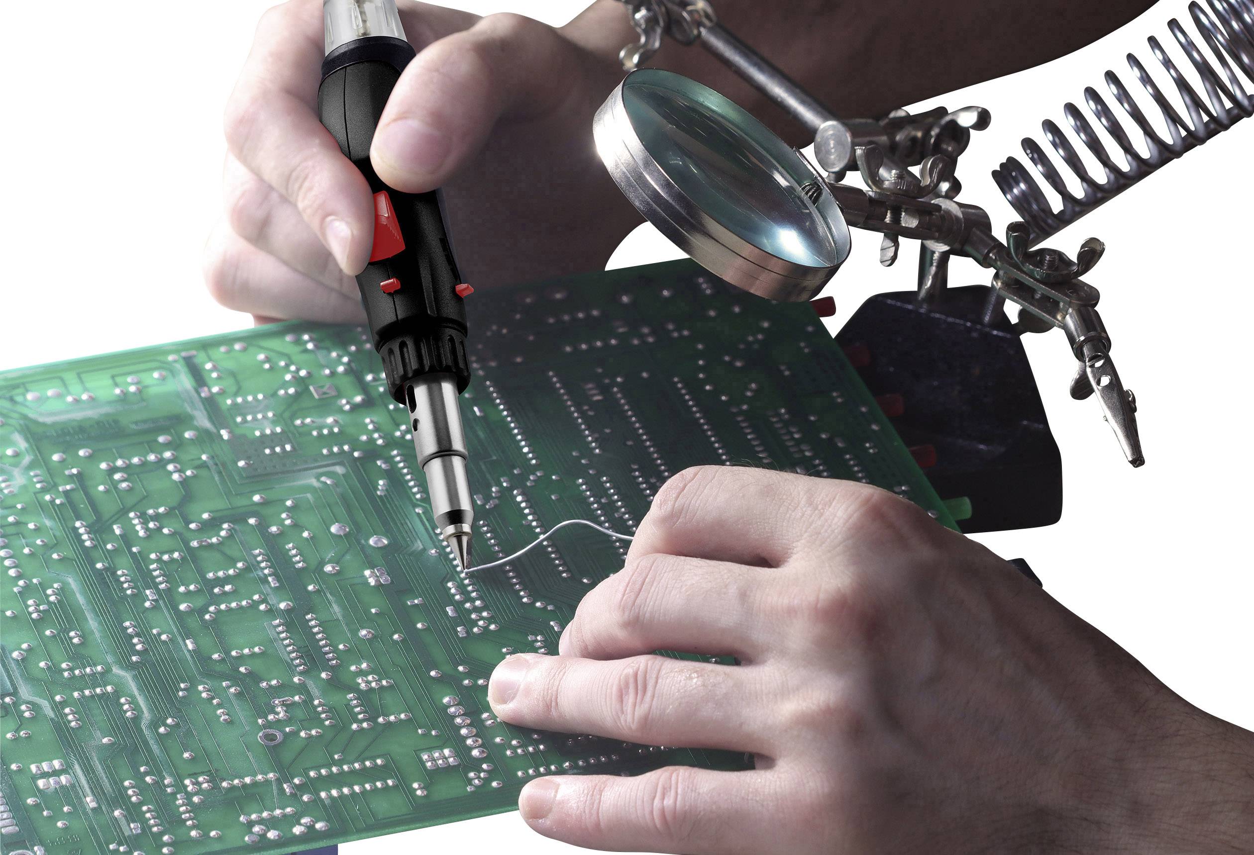 'Detailný záber rúk, ktoré spájkujú zelenú dosku plošných spojov pomocou spájkovačky, so zväčšovacím sklom a svorkou pre stabilizáciu.'