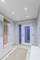 Chodba s bielymi vstupnými dverami, malým kobercom, bielou vstavanou skriňou s dreveným obložením a vešiakmi, svetlým stropom so spots osvetlením.