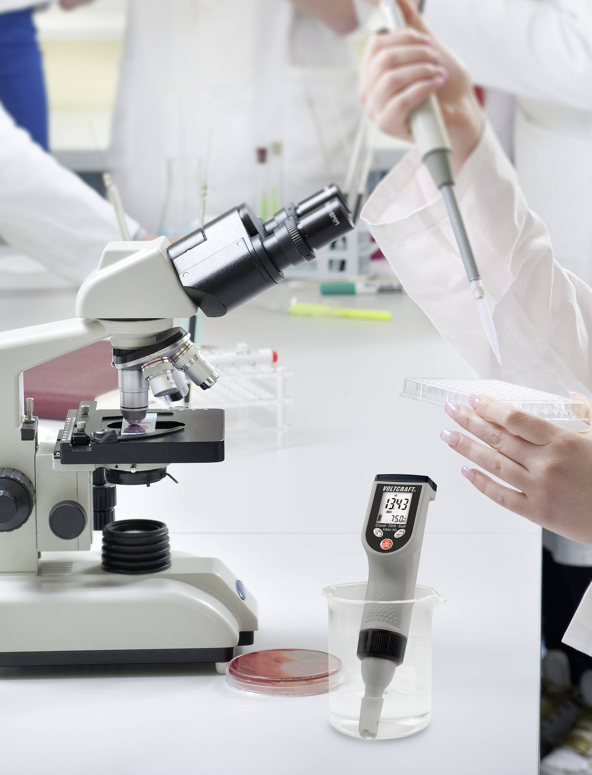 Vedci v laboratóriu používajú mikroskop a pipetu na analýzu vzoriek, digitálny prístroj zobrazuje namerané hodnoty.