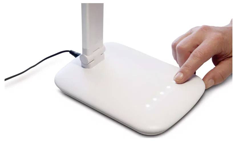 Ruka sa dotýka bieleho zariadenia s LED indikátormi, pravdepodobne tlačidlom napájania, s moderným, minimalistickým dizajnom, prepojené káblom.