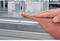 Ruka obrába kovovú hranu brúsnym papierom na pracovnom stole, aby vytvorila hladký povrch.