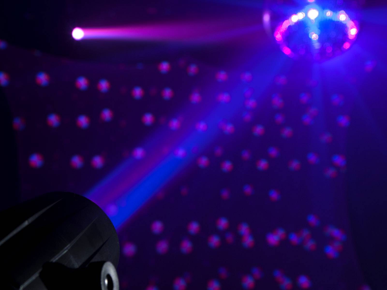 Diskogula vyžaruje pestré svetelné lúče v tmavej miestnosti a vytvára živú a slávnostnú atmosféru.