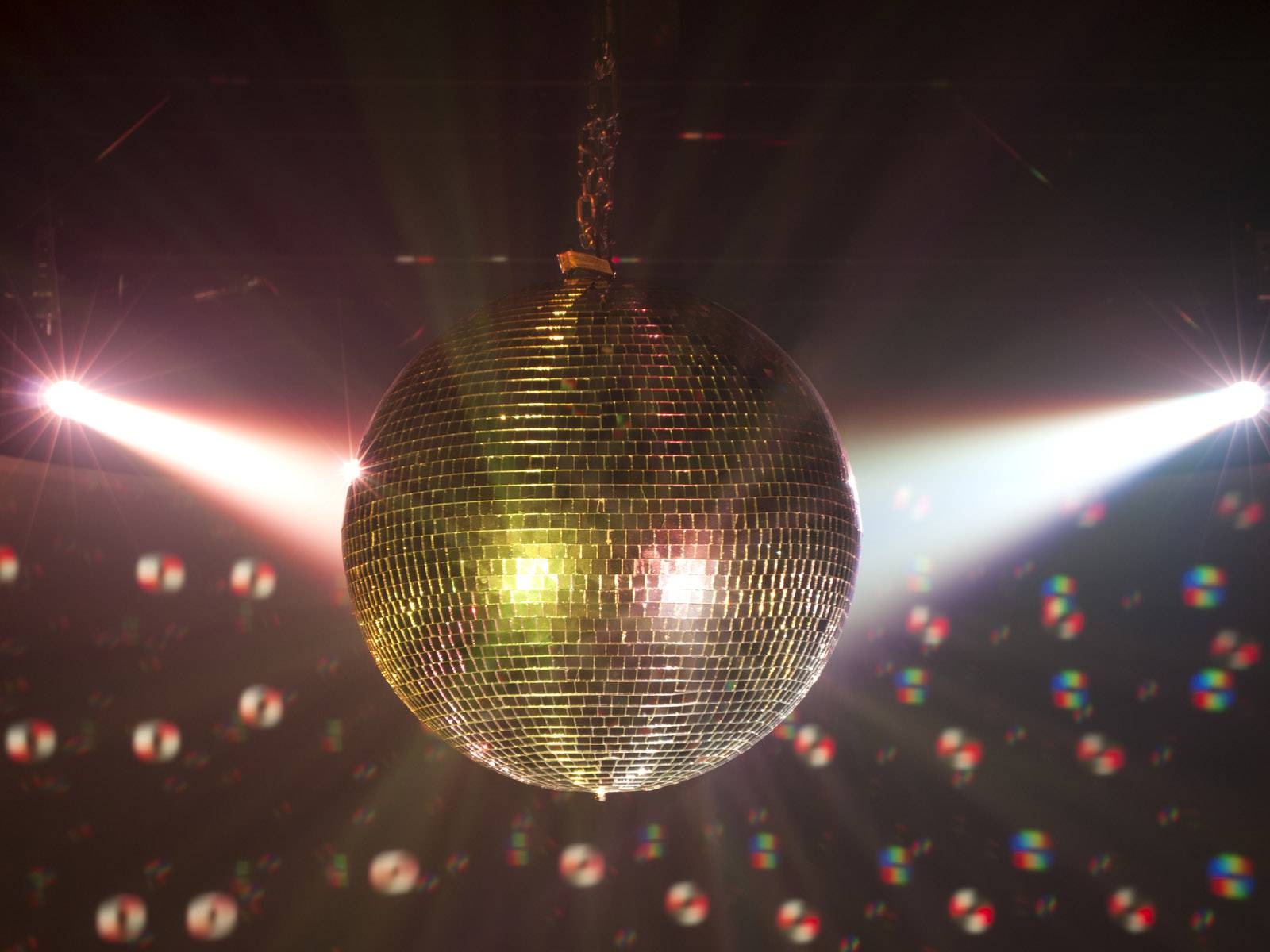 Na strope visí trblietavá diskotéková guľa, ktorá odráža pestrofarebné svetlá a vytvára živelnú atmosféru.