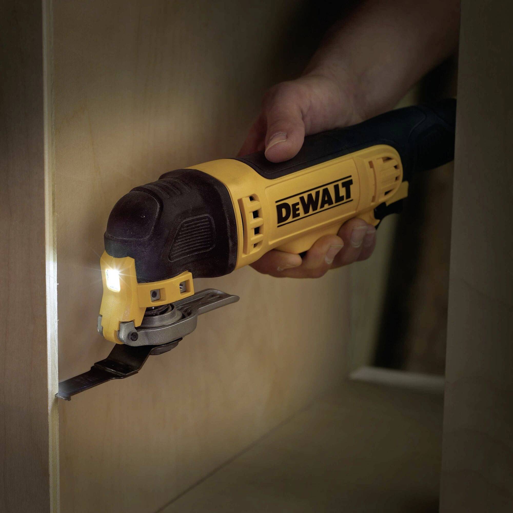 Osoba používa žlté elektrické náradie značky DEWALT na rezanie dreva vo vnútri skrine.