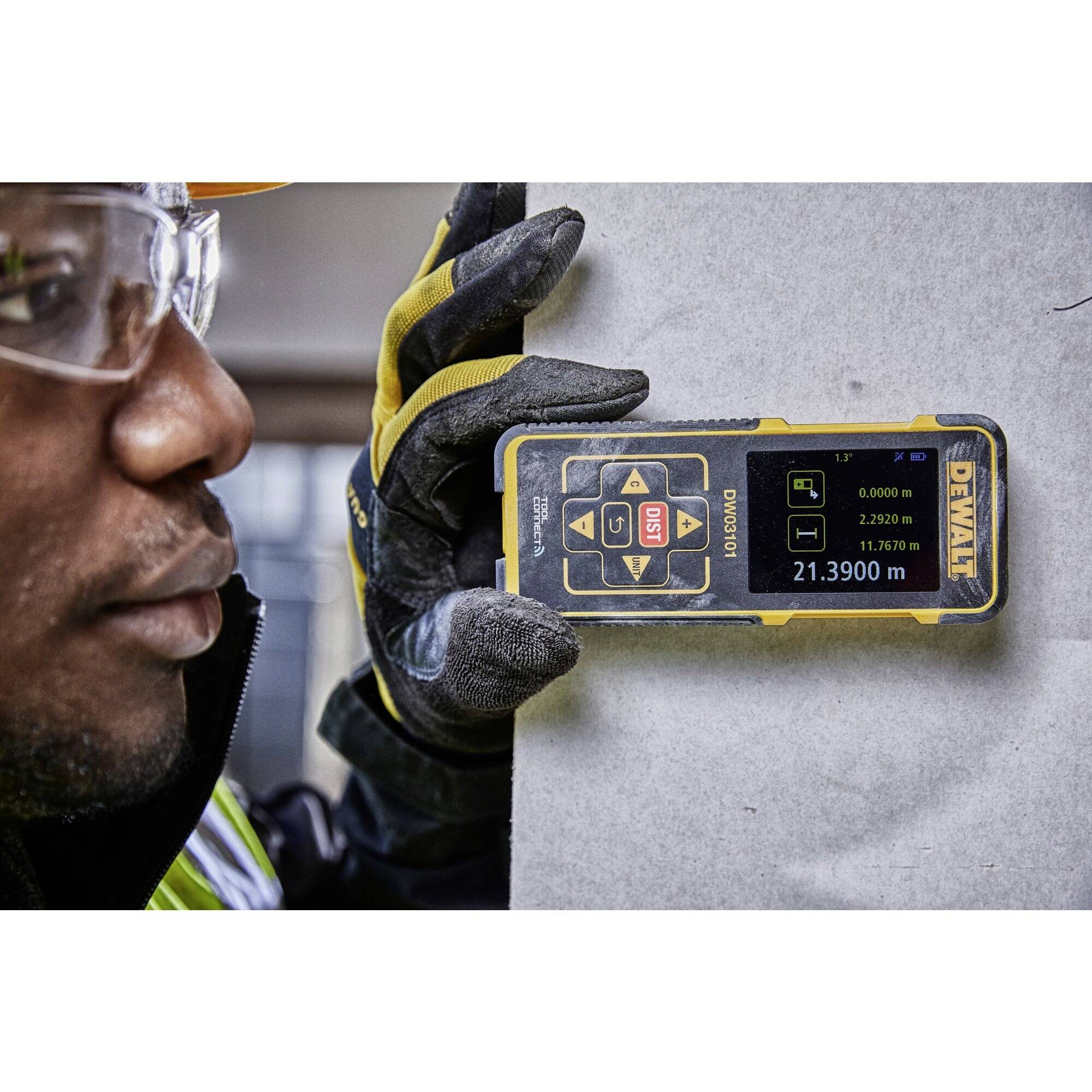 Osoba meria digitálnym zariadením pri stene. Na displeji zariadenia sú viditeľné rôzne namerané hodnoty.