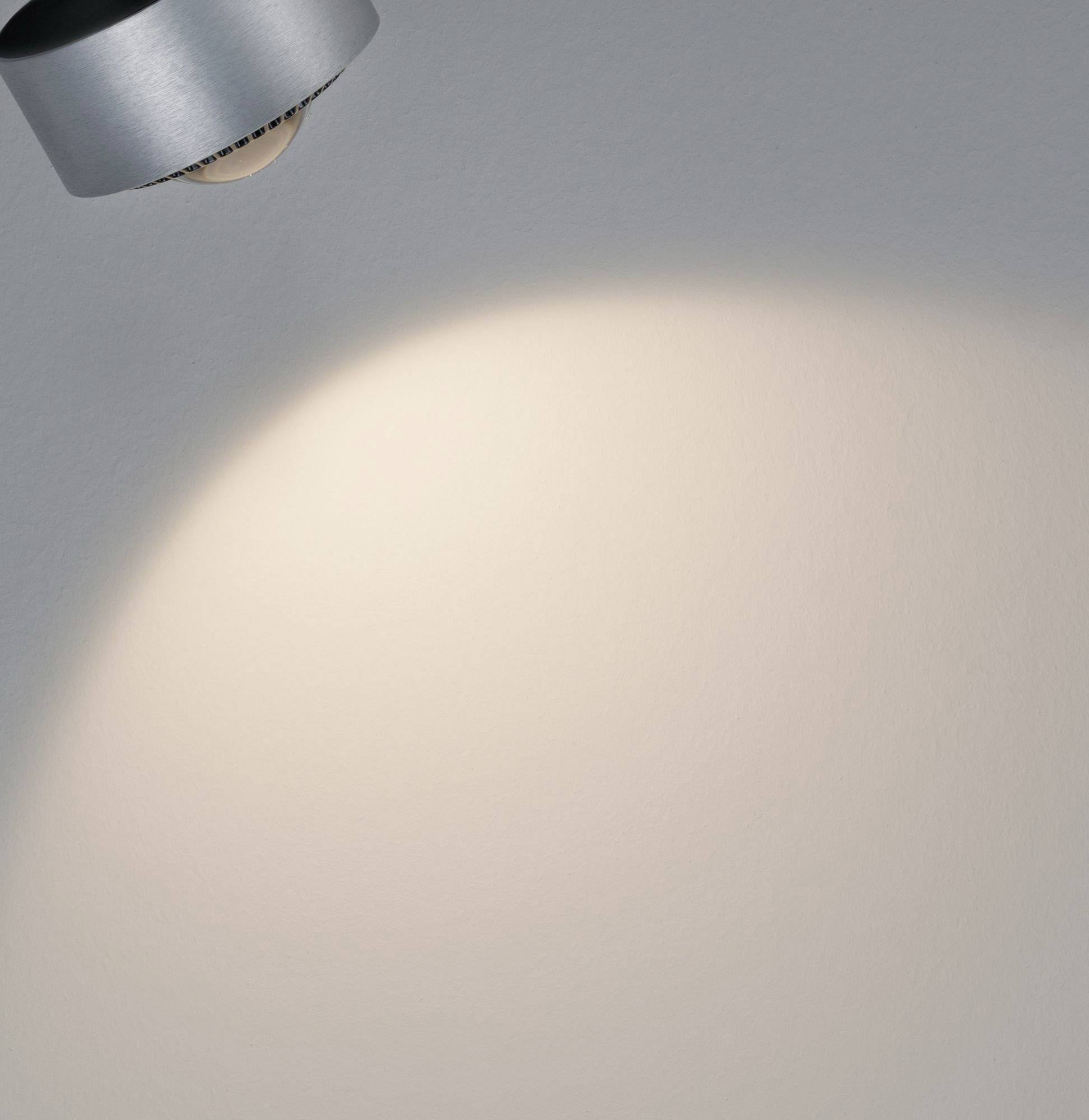 Lampa osvetľuje prázdne šedé pozadie.