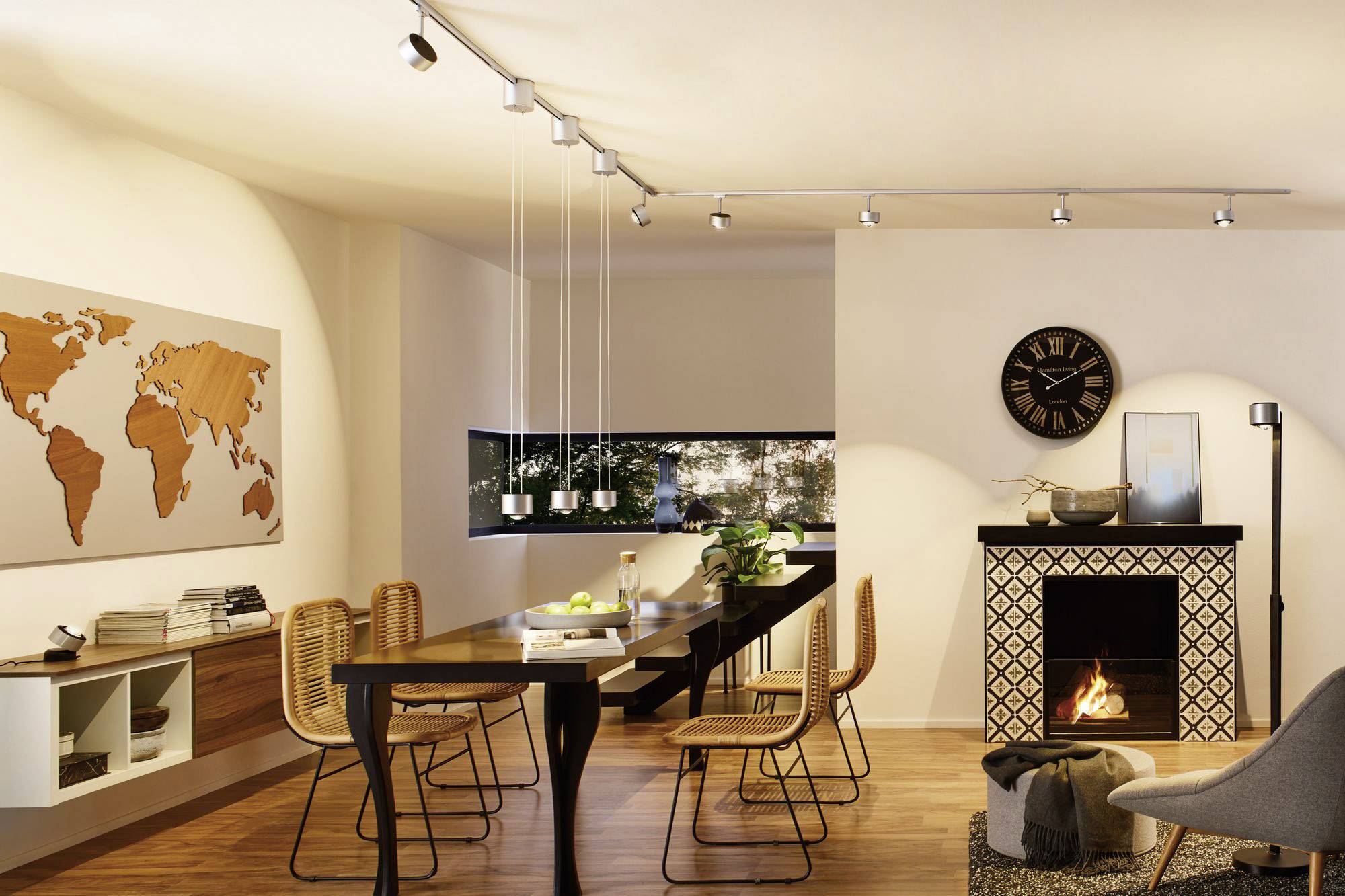 Moderná obývačka so stolom a stoličkami, svetovou mapou na stene, krbom s ohňom a štýlovým osvetlením.