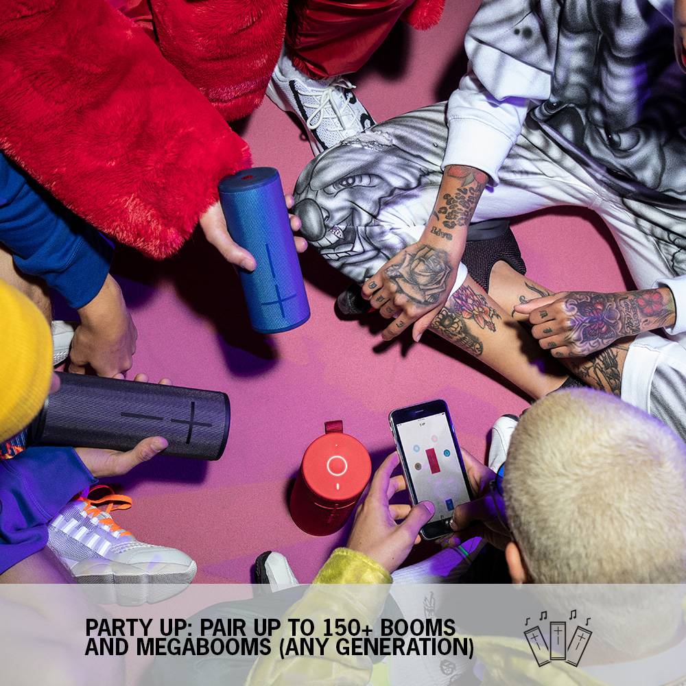 Červený reproduktor stojí vedľa veže z naplnených šampanských pohárov. Text na obrázku: '15H výdrž batérie + 45M dosah'.