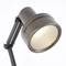 Priemyselná stojaca lampa s kovovým tienidlom a nastaviteľným ramenom. Lampa vyžaruje teplé svetlo a má funkčný, minimalistický dizajn.