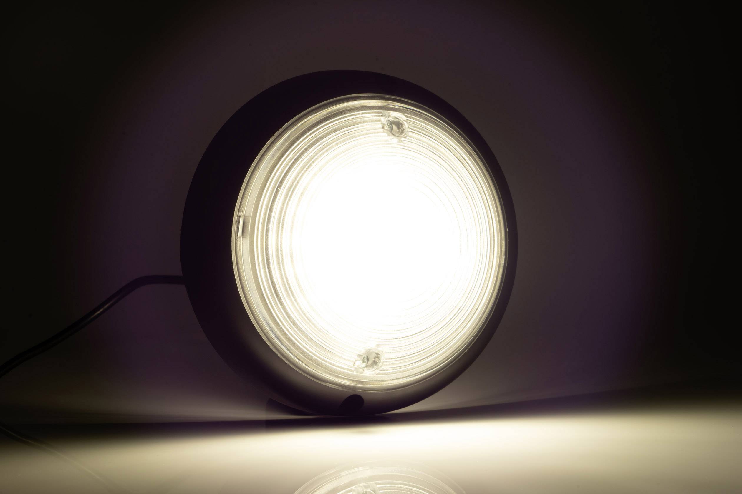 Jasné, okrúhle svetlo žiari z lampy, ktorá stojí na povrchu. Pozadie je tmavé.