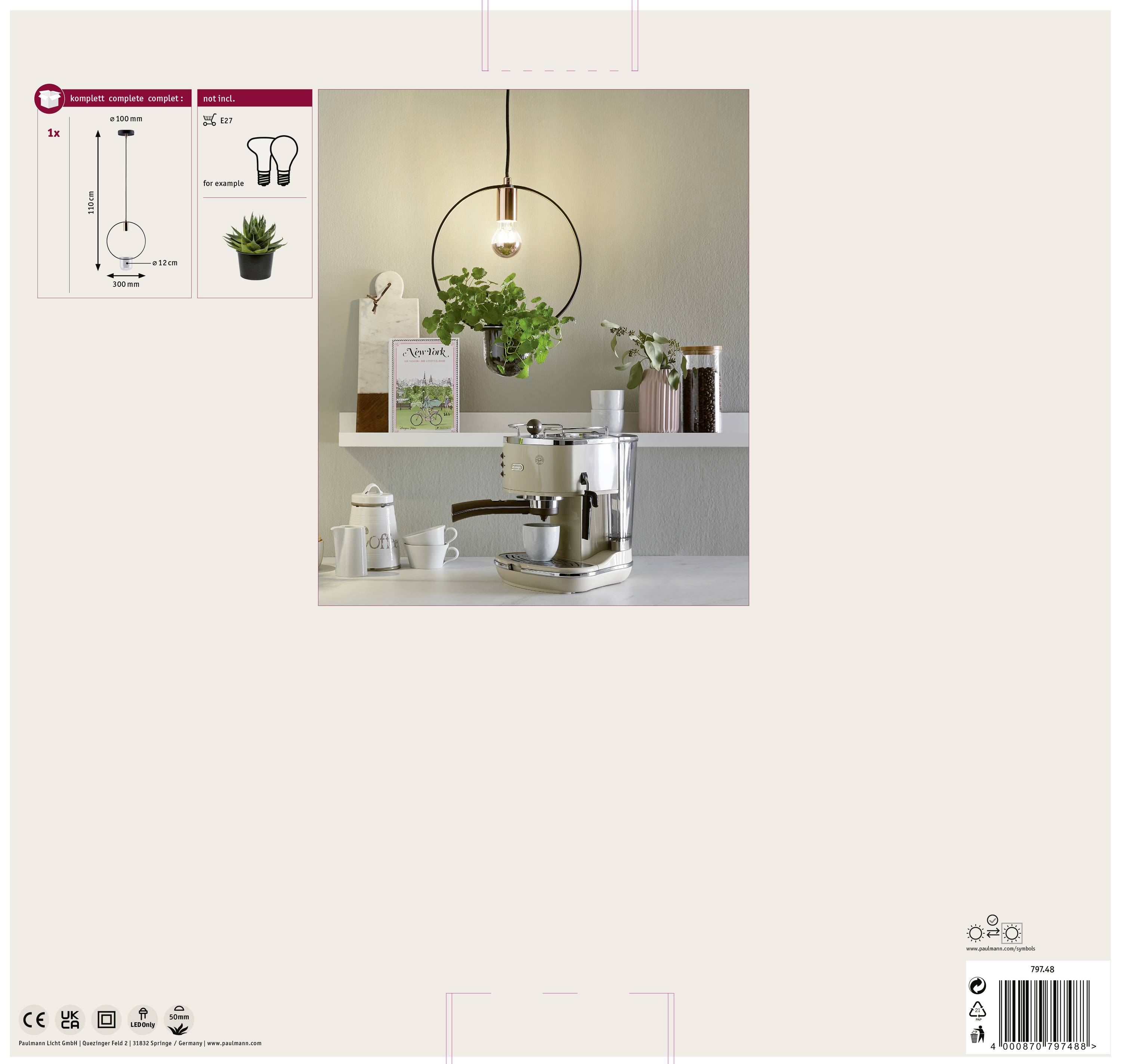 Jednoduchá biela kuchyňa s lampou upevnenou na stene, prístrojom na prípravu kávy na pulte a rastlinami v pozadí.