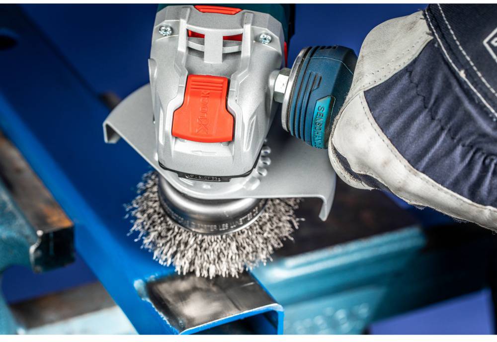 Drôtená kefa je priložená k kovovému povrchu s pomocou elektrického nástroja, aby sa povrch vyčistil alebo vyleštil.