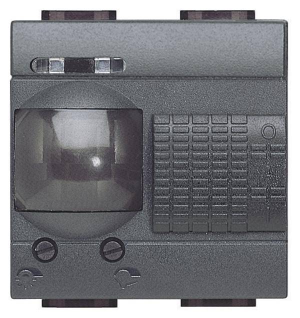 Snímač pohybu v sivom kryte, štvorcový tvar. Obsahuje senzorový objektív vľavo, obdĺžnikový vzor vpravo.