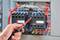 Ruka s elektrickým skrutkovačom kontroluje elektrické obvody v otvorenom rozvádzači. Farebne kódované káble sú viditeľné.