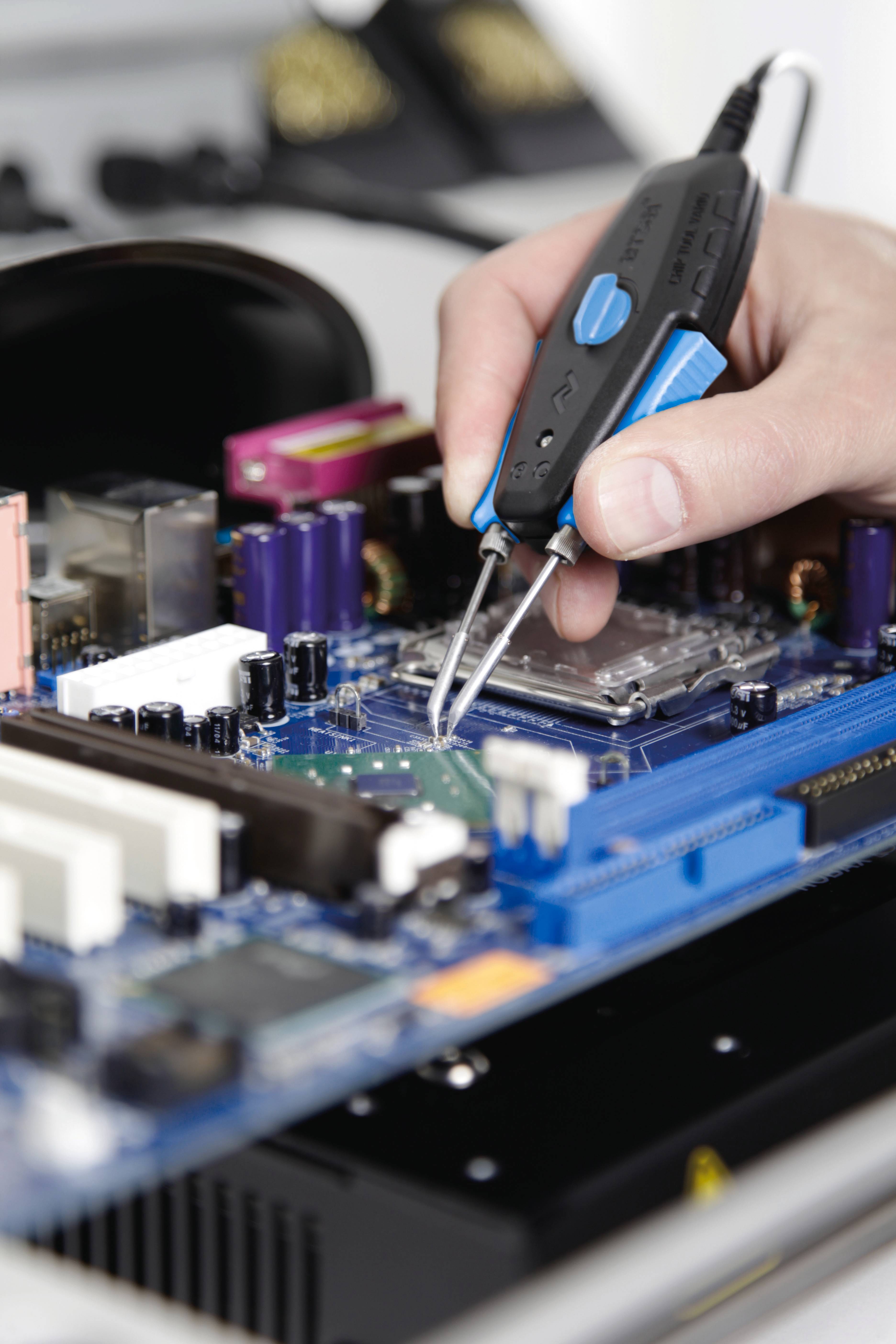 Ruka používa multimeter na meranie napätia na doske elektronického obvodu. Doska obsahuje rôzne elektronické komponenty.