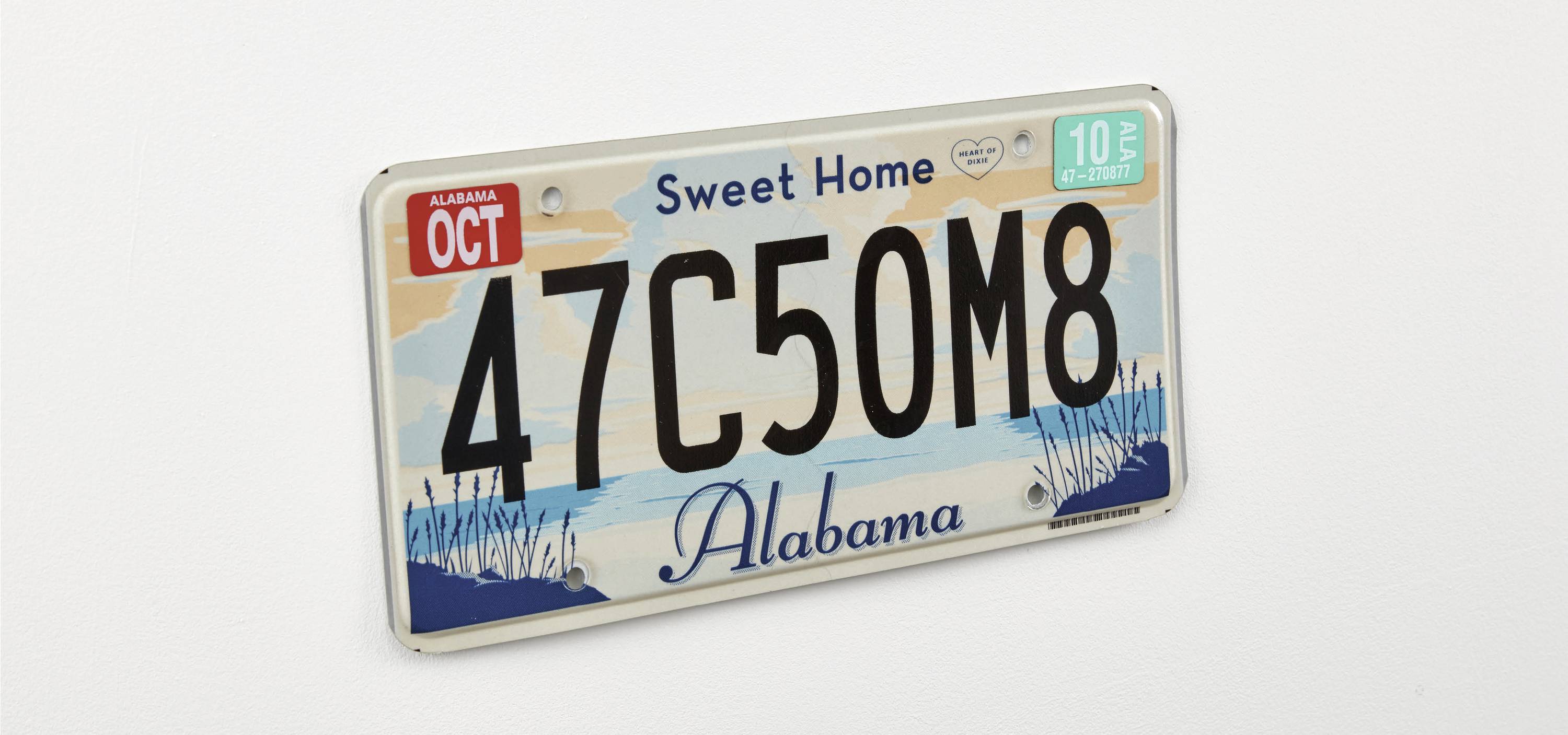 Evidenčná tabuľka z Alabamy s nápisom 'Sweet Home Alabama' a evidenčným číslom '47C50M8'. Vľavo hore nálepka z mesiaca október.