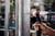 Osoba drží vŕtačku a vŕta dieru do kovového rámu. Prostredie naznačuje, že sa nachádza v dielni.