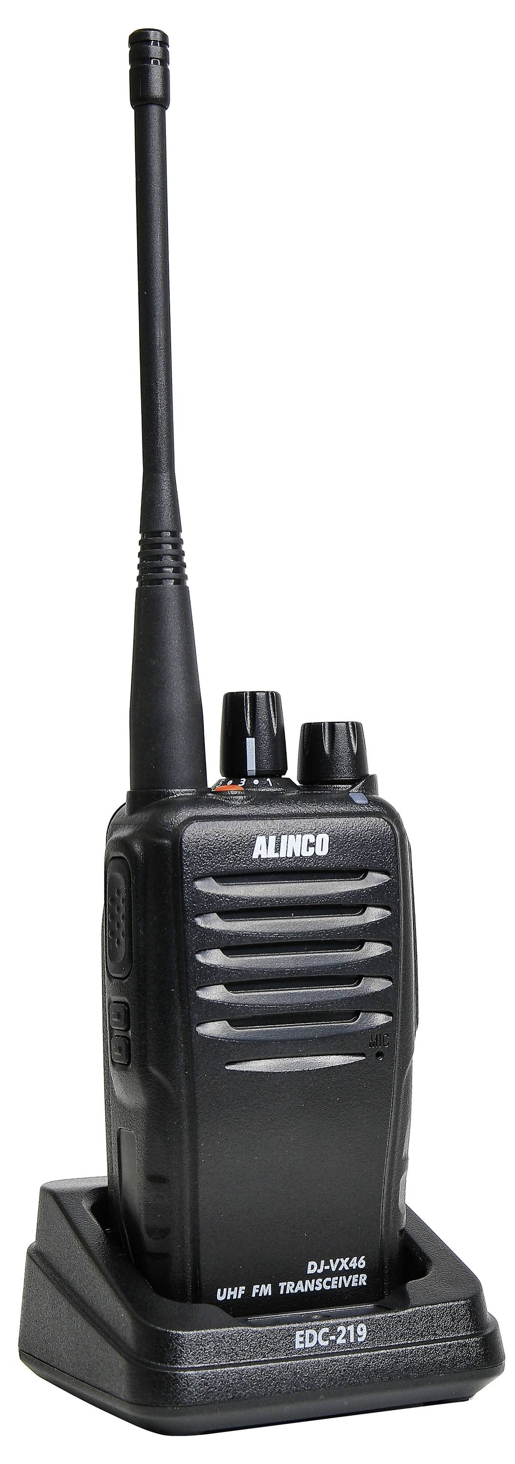 Čierna ručná rádiostanica značky Alinco stojí na nabíjacej stanici. Má dlhú anténu a dva otočné gombíky na hornej strane.