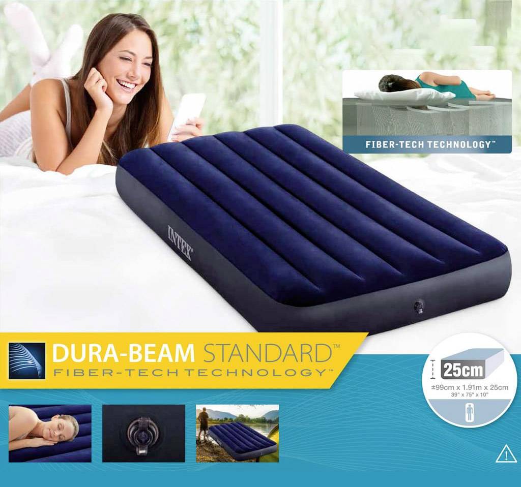 Na posteli leží tmavmodrá nafukovacia matrac. V pozadí sa usmieva žena. Dole je napísané 'Dura-Beam Standard Fiber-Tech Technology'.