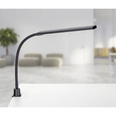Čierna flexibilná LED stolná lampa na bielom stole v modernej, minimalistickej miestnosti s rozmazaným pozadím.