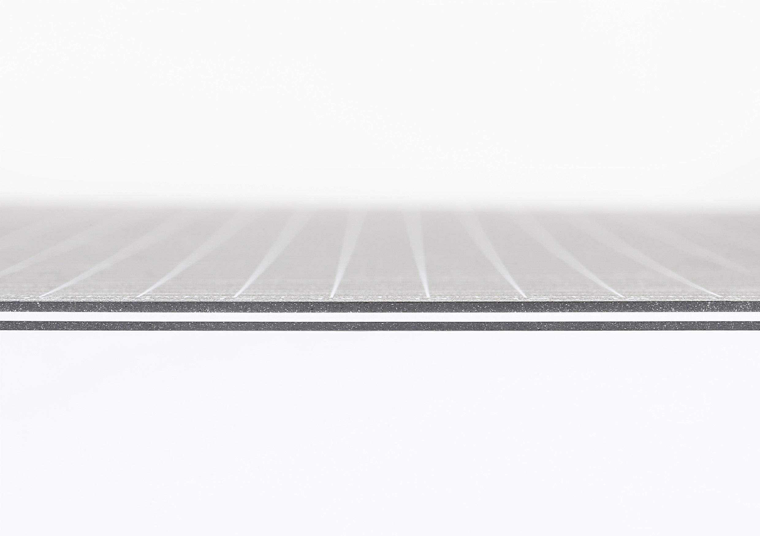 Tenká, šrafovaná kovová platňa v detailnom zábere na bielom pozadí zobrazuje minimalistickú a modernú štruktúru.