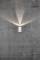 Strieborná nástenná lampa na sivej betónovej stene svieti nahor a nadol a vytvára krížový svetelný vzor.