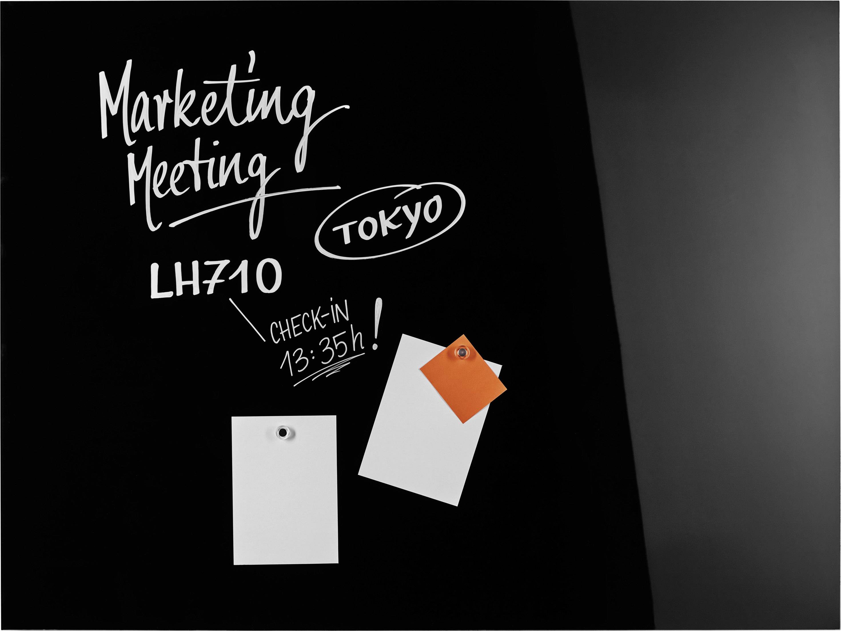 Čierna tabuľa s nápisom 'Marketing Meeting', 'Tokio', let 'LH710', 'Check-in 13:35h'. Dva prázdne poznámkové lístky pripevnené.