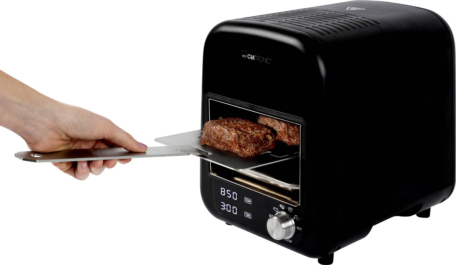 Jedna ruka vyťahuje podnos s dvoma steakmi z malej čiernej rúry. Rúra ukazuje teplotu 850 stupňov.