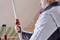 Muž nastavuje tyč na stavenisku. Má na sebe bundu a pracuje na strope miestnosti.