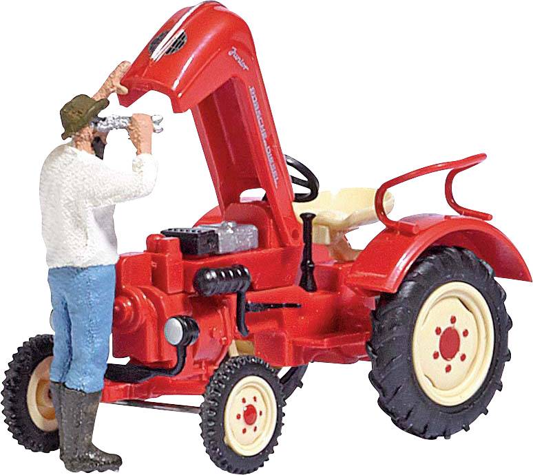 Miniatúrna figúrka muža, ktorý opravuje červený traktor so zdvihnutou kapotou motora. Muž má na sebe čižmy a klobúk.