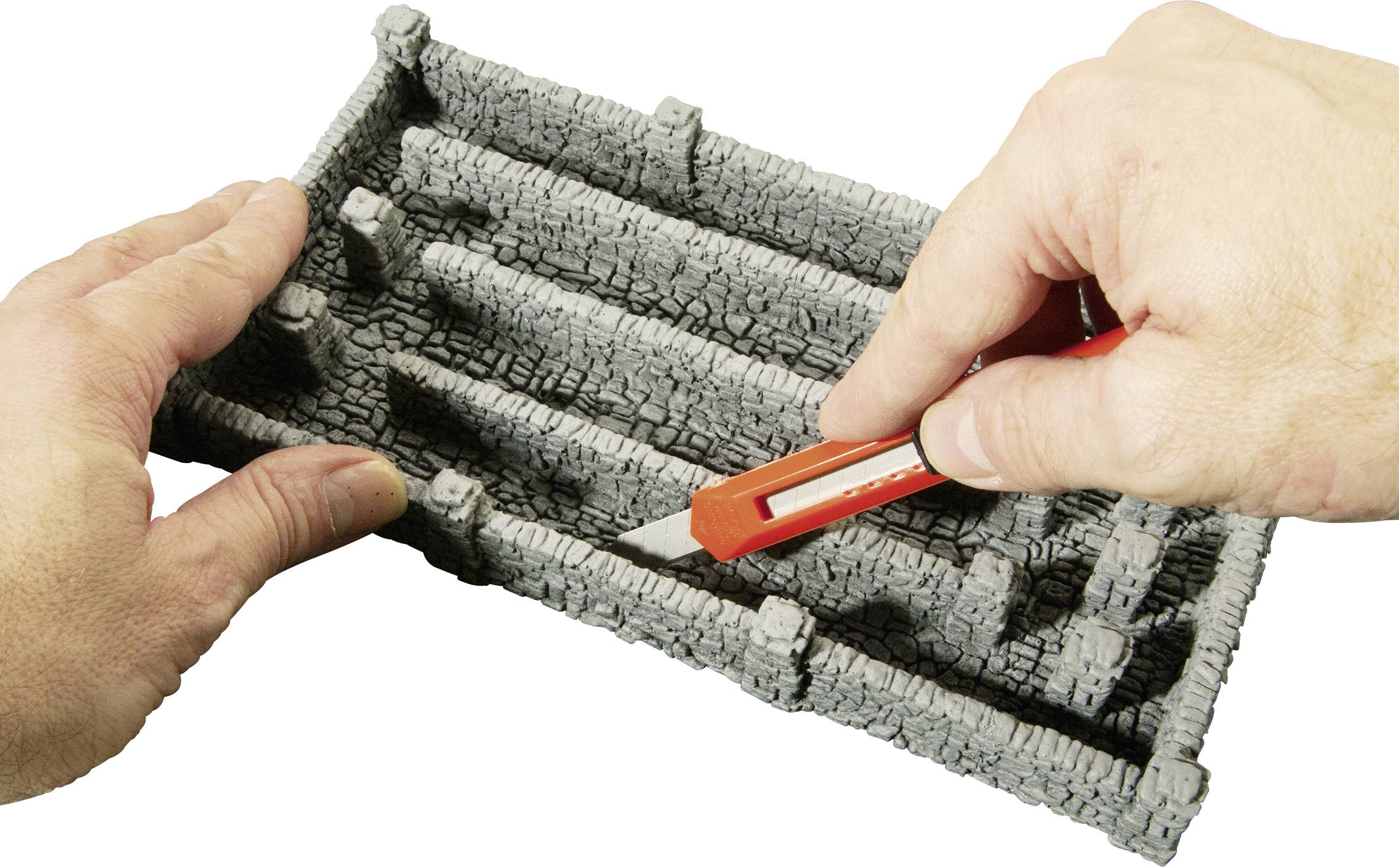 Ruky držia obdĺžnikový, kamennému podobný labyrint, pričom doň zasúvajú červenú plastovú kartu.