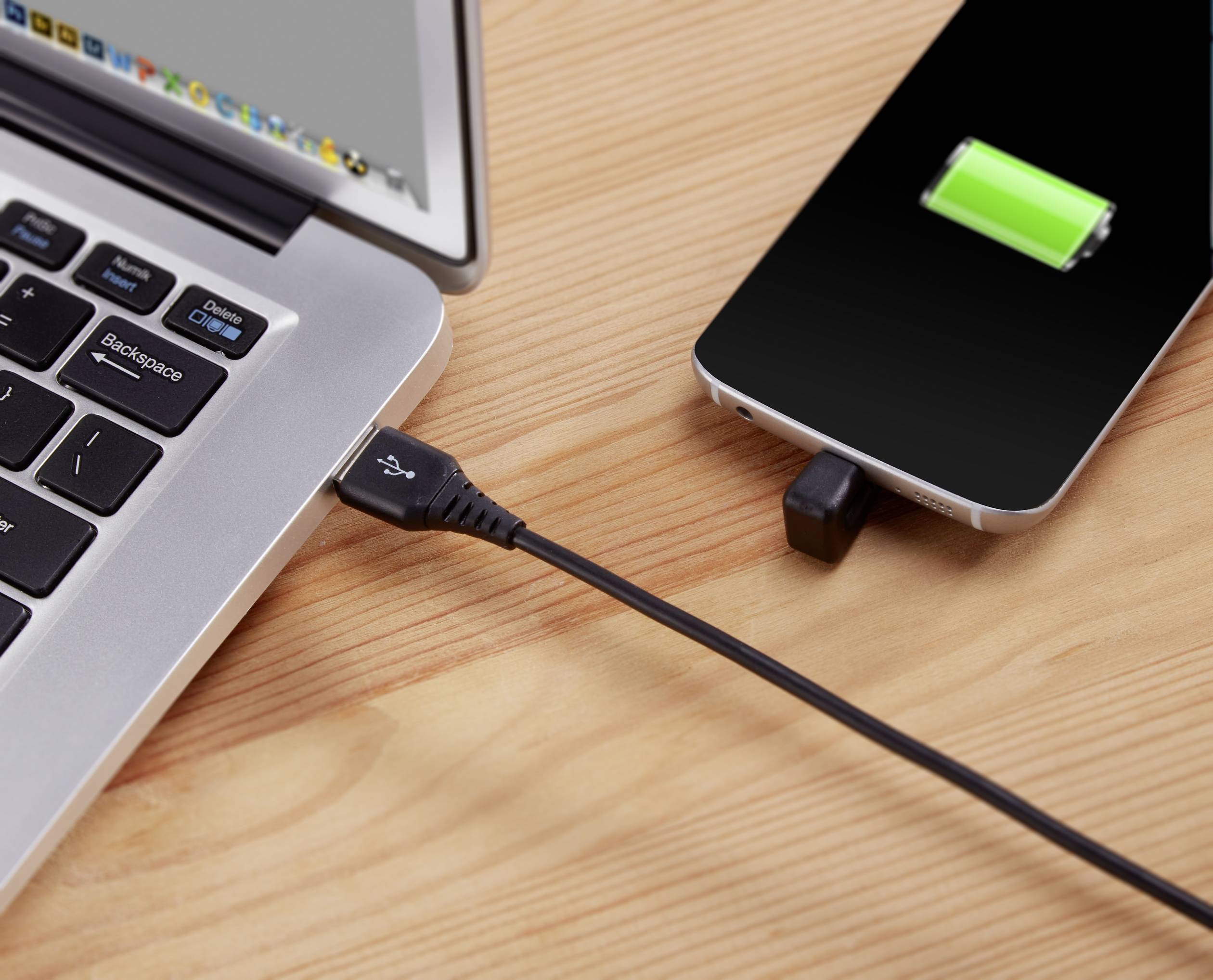 Smartfón sa nabíja cez USB kábel na laptope, zelený symbol batérie ukazuje stav nabitia.
