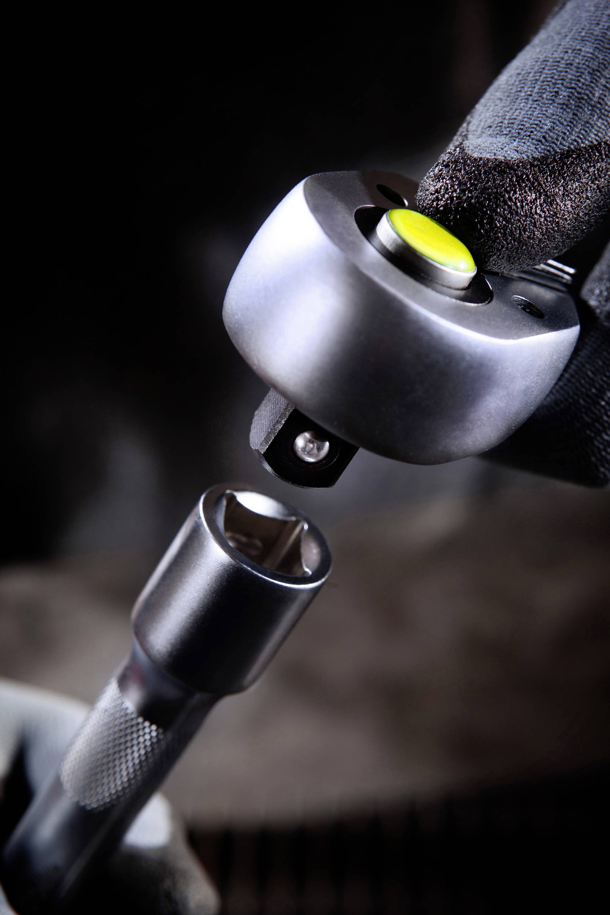 Detailný záber ruky, ktorá používa kovový nástrčný kľúč na upevnenie skrutkovej skrutky. Zameranie je na nástroj.