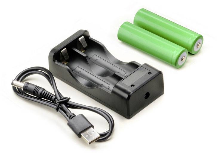 USB nabíjačka batérií, zobrazená s dvomi zelenými batériami AA a USB nabíjacím káblom.
