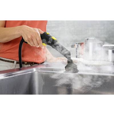 Osoba čistí kuchynskú drezu parným čističom. Para stúpa, zatiaľ čo kefa prechádza po povrchu.
