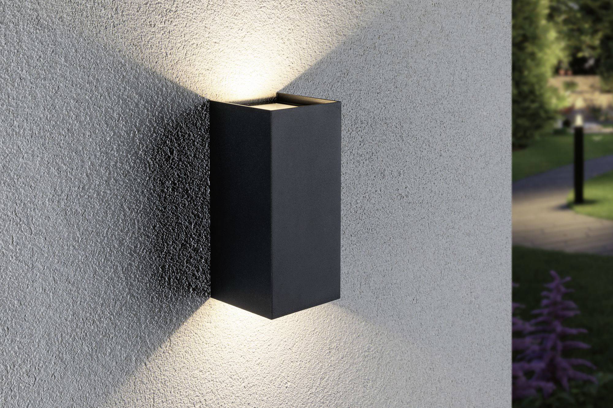 Moderná vonkajšia nástenná lampa s obdĺžnikovým dizajnom vyžaruje svetlo nahor a nadol, namontovaná na sivej stene.