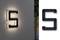 Písmeno "S" z čierneho, LED podsvietného materiálu na sivej stene. Vedľa vpravo vo vypnutom stave.
