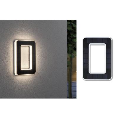 Solárna nástenná lampa svieti na vonkajšej stene. Vpravo vedľa lampy je umiestnený solárny panel.