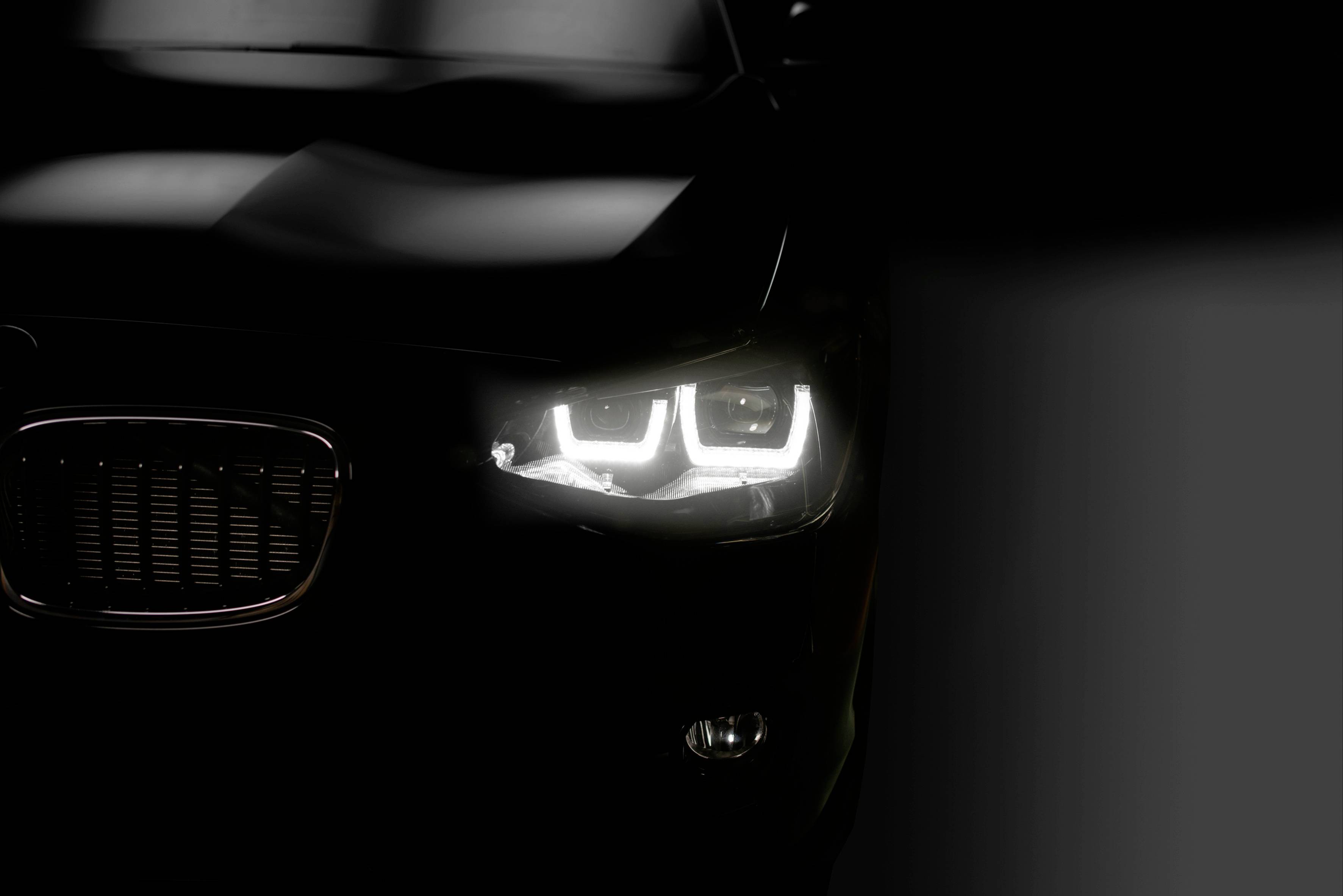 Detailný záber svetlometu automobilu so svietiacimi LED svetlami v tme.