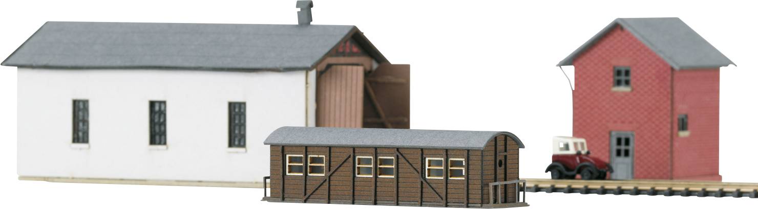 Tri modelové budovy: jedna biela budova, hnedý sklad a červená budova. Malý nákladiak stojí vedľa nich.