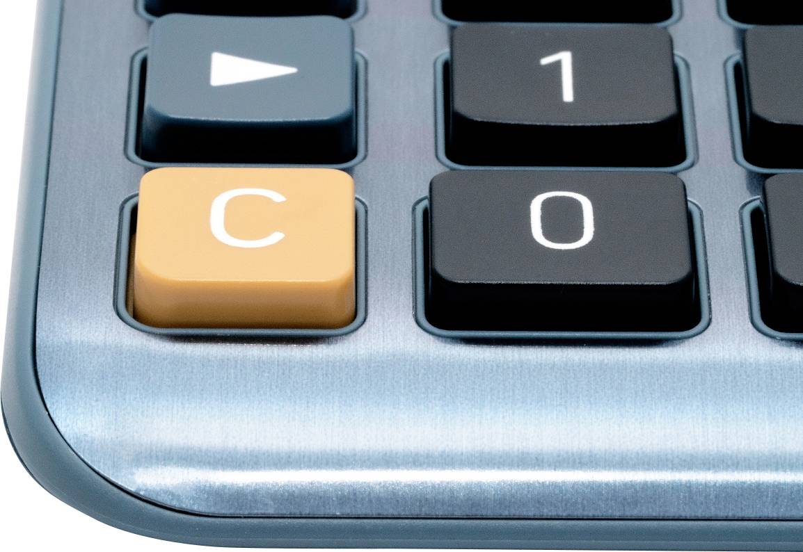 Detailný záber klávesnice kalkulačky so zvýrazneným oranžovým tlačidlom 'C', obklopeným čiernymi numerickými tlačidlami.