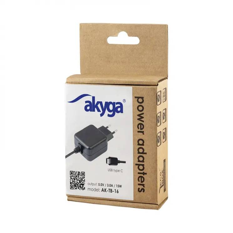 Hnedá kartónová škatuľa s nápisom 'akyga power adapters'. Na obale je zobrazený sieťový adaptér a USB-C kábel. Model: AK-TB-16, Výstup: 5V / 3A / 15W.