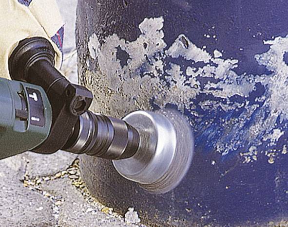 Uhlová brúska sa používa na odstránenie farby z kovového valca. Brúsny kotúč sa rýchlo otáča po povrchu.