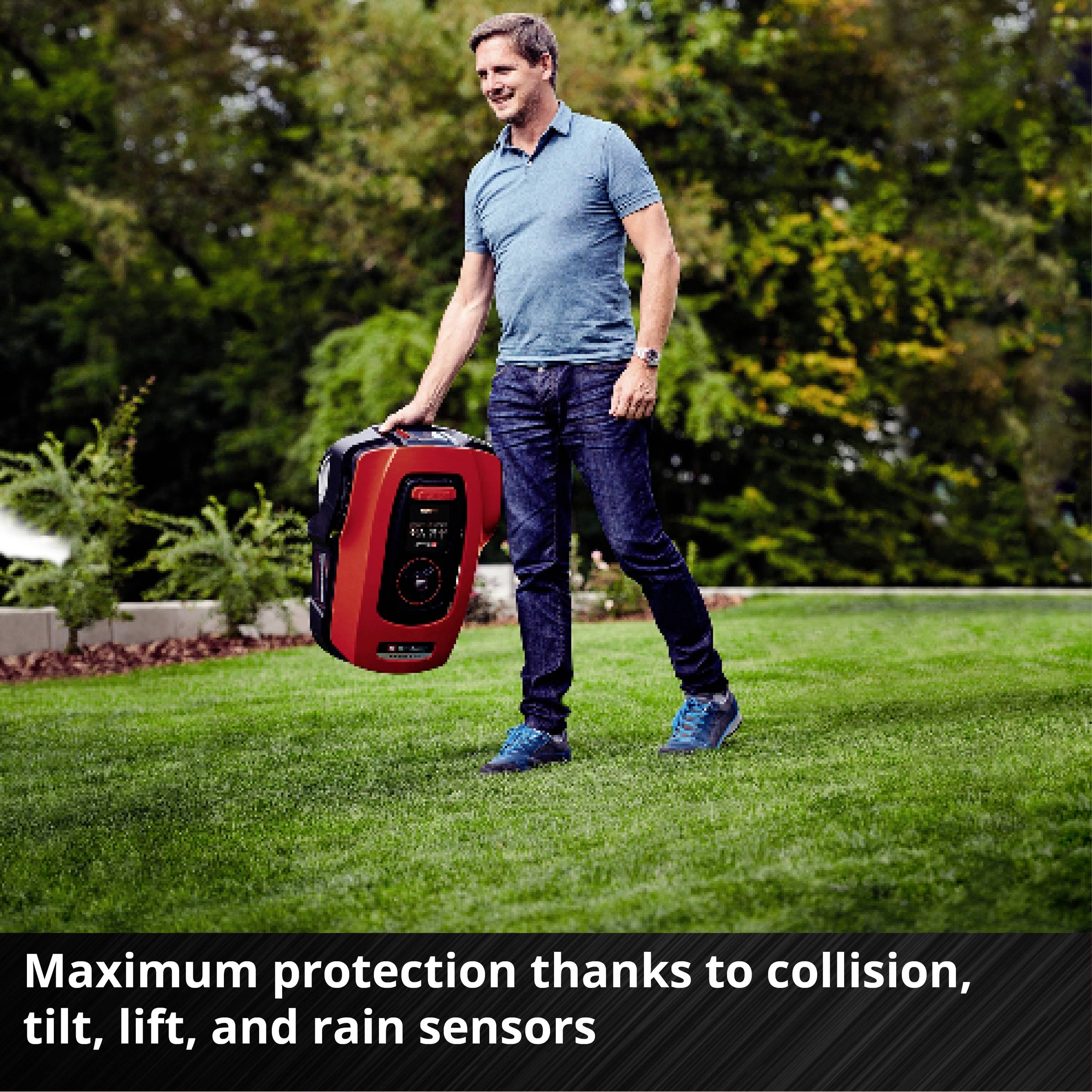 Muž v polo tričku stojí na trávniku a drží robotickú kosačku. Text v obraze: 'Maximálna ochrana vďaka senzorom nárazov, náklonu, zdvihu a dažďa'.