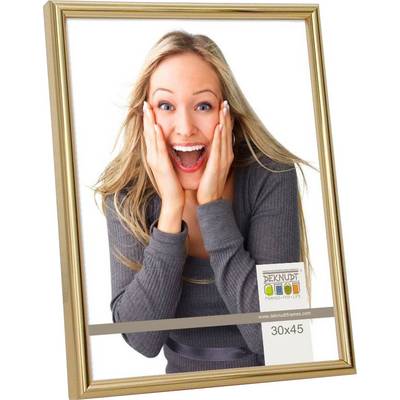 Usmiata osoba si drží ruky na tvári v zlatom ráme. Text na obrázku: 'DEKNUDT FRAMES FOR LIFE', Veľkosť: 30x45.
