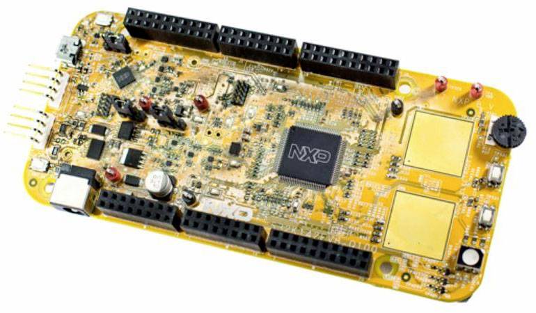 Žltá vývojová doska s čipom NXP uprostred a niekoľkými portmi a konektormi pre elektronické komponenty.