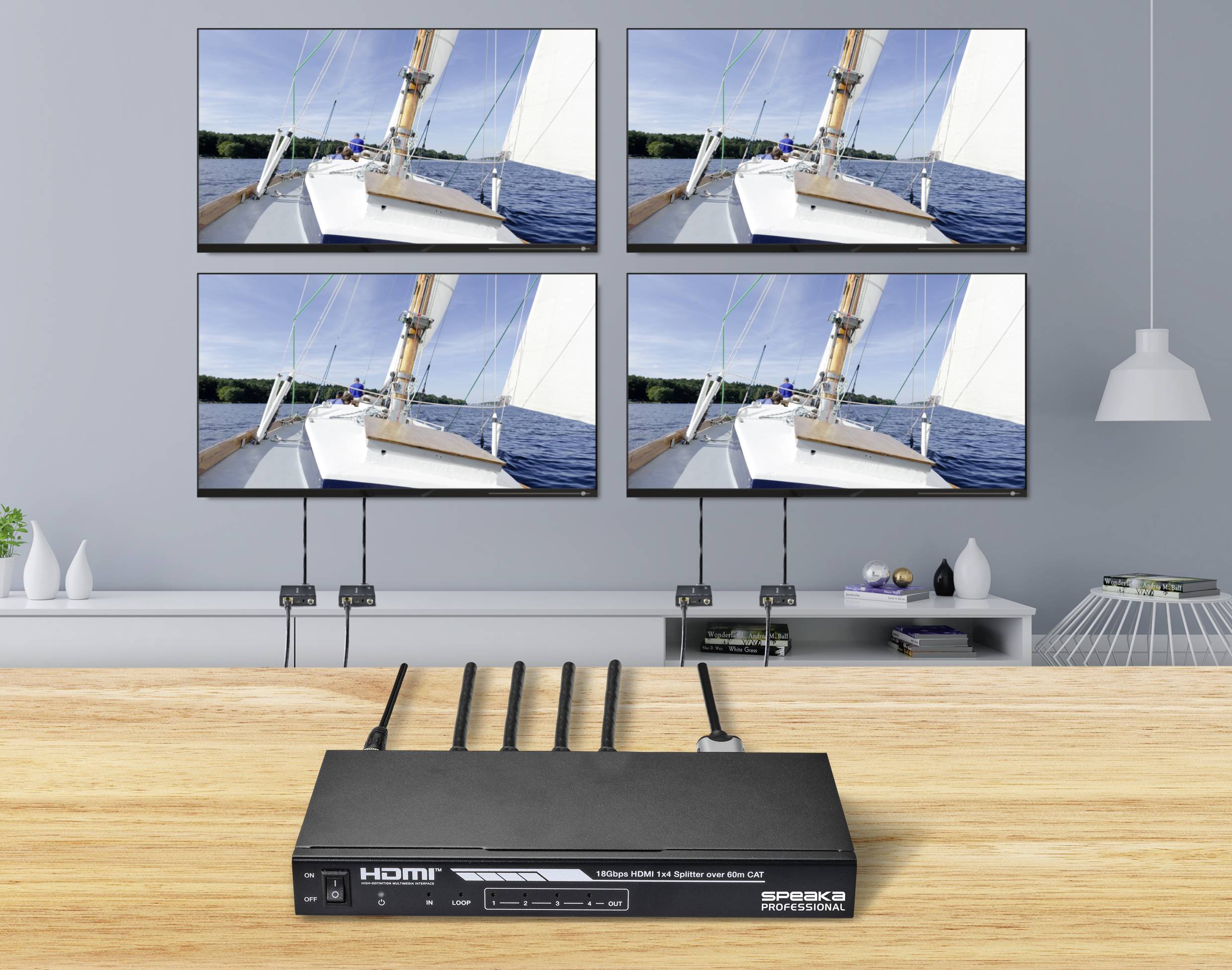 Štyri monitory zobrazujú ten istý obraz plachetnice na mori. Pod nimi leží HDMI rozbočovač s niekoľkými pripojenými káblami.