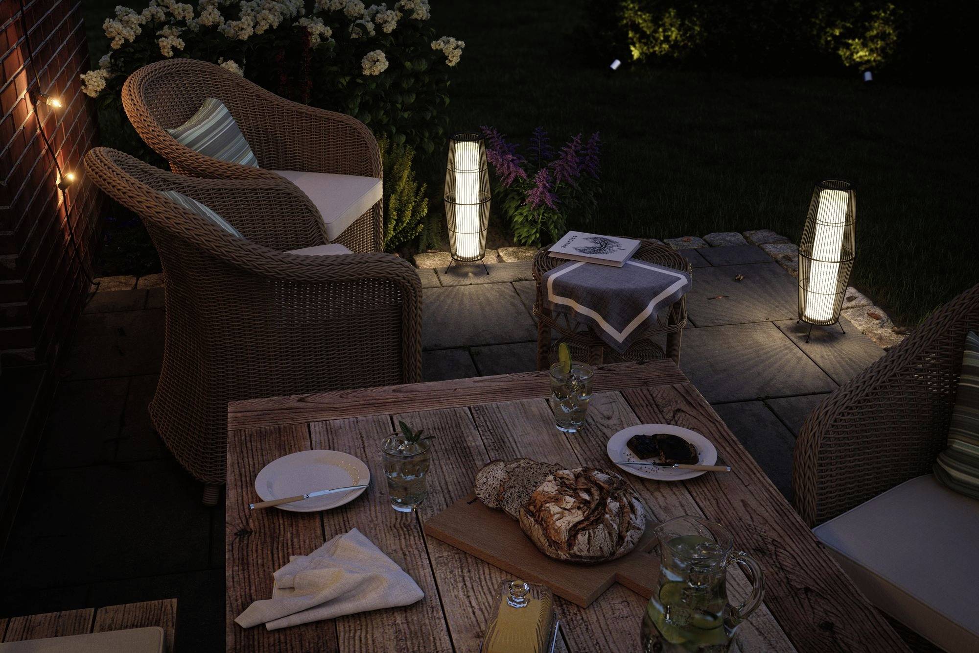 Útulný vonkajší priestor s drevenou terasou večer, ratanovým nábytkom, osvetlením a chlebom na stole v uvoľnenej atmosfére.